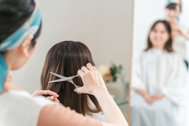 美容室で髪を切る・カットする美容師の女性