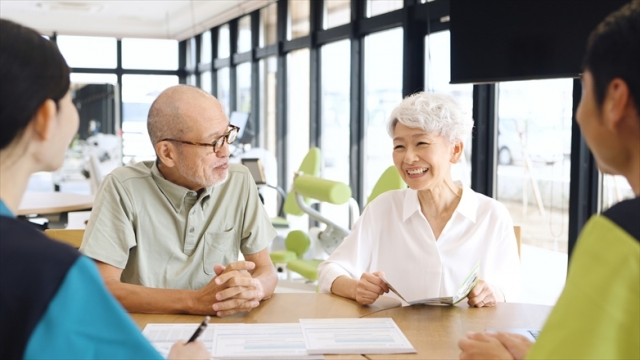 介護施設の説明を受けるアジア人高齢者